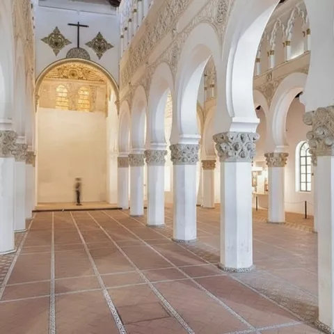 Nave amplia con arquerías sucesivas y suelo de baldosas geométricas.