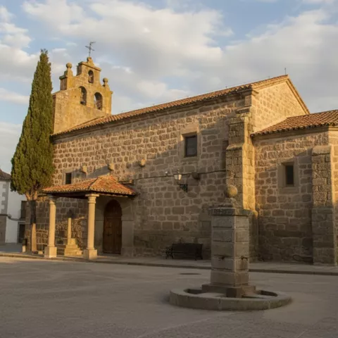 Vista exterior de una iglesia antigua construida con piedra, con un campanario y un pórtico de entrada