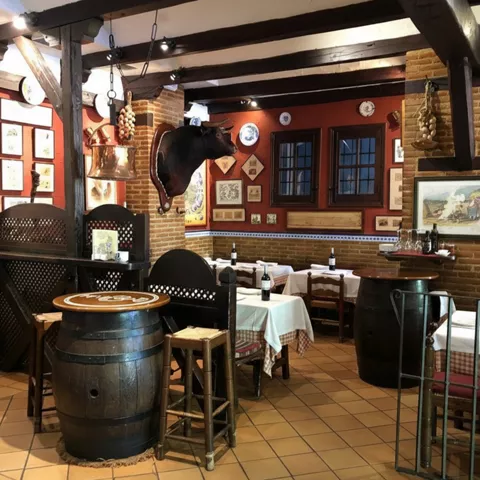 Salón tradicional con barriles, vigas de madera y mesas preparadas.