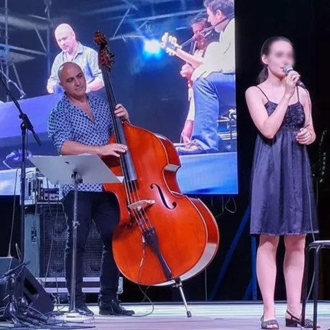 Banda de jazz con cantante y músicos actuando ante gran pantalla.