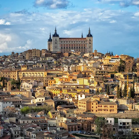 Ciudad antigua escalonada en una colina con fortaleza dominante.