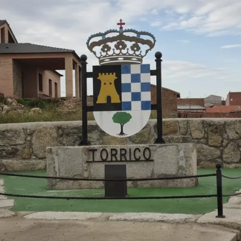 Escudo institucional sobre pedestal de piedra en espacio urbano