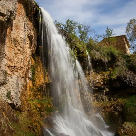 Cascada natural cayendo entre rocas y vegetación