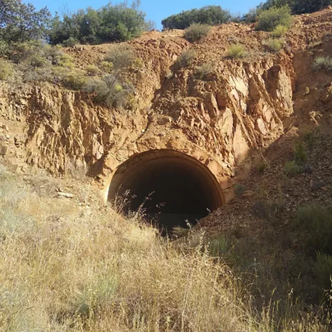 Boca de túnel ferroviario abandonado en talud rocoso
