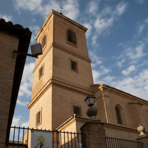 Torre de iglesia de ladrillo vista desde la calle bajo cielo azul