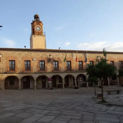 Fachada principal de un edificio histórico de piedra con soportales de arcos de medio punto.