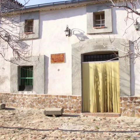 Fachada encalada con puerta principal y banco de piedra