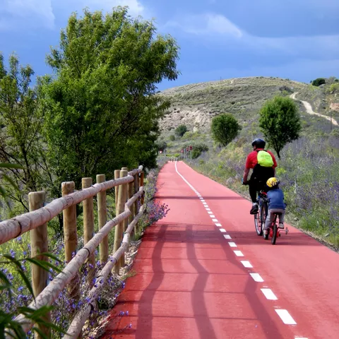Carril bici entre colinas y vegetación.
