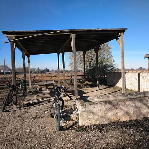 Área de descanso con mesas, bicis y refugio de madera