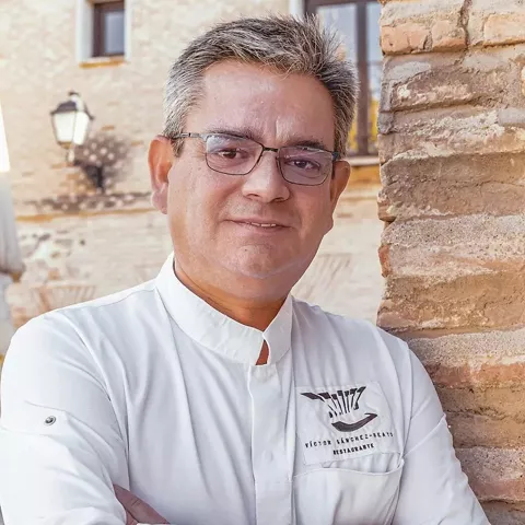 Retrato de cocinero con brazos cruzados junto a una pared de ladrillo
