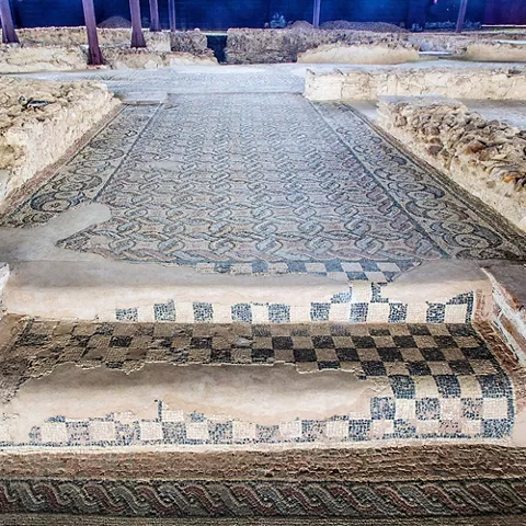 Pavimento de mosaico con motivos geométricos en una estancia excavada.
