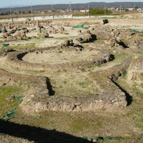 Restos arqueológicos con muros circulares y estructuras de piedra al aire libre.