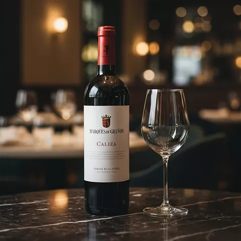 Botella de vino tinto y copa vacía sobre una mesa de madera