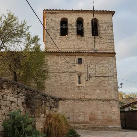Torre campanario junto a muro de piedra