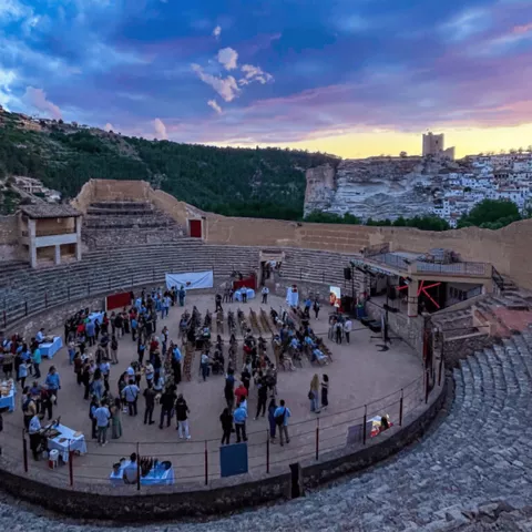 Evento cultural al aire libre en un anfiteatro histórico al atardecer