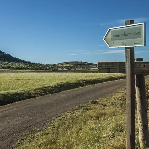 Camino rural con señal informativa y colinas