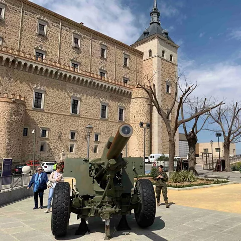 Pieza de artillería histórica expuesta en una plaza junto a un edificio de piedra.