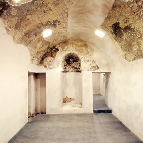 Habitación con techo abovedado y restos de pintura original sobre muros claros.