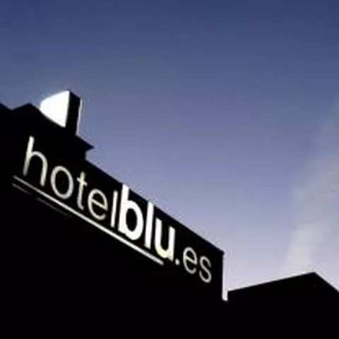 Rótulo luminoso en la azotea de un edificio al atardecer.