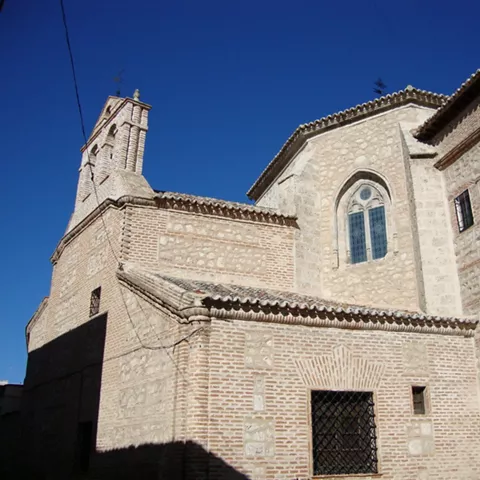 Fachada lateral de iglesia de ladrillo y piedra con campanario