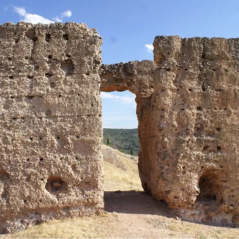 Dos muros de piedra erosionada unidos por un vano elevado.