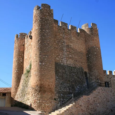 Torre fortificada de piedra con almenas bajo cielo despejado.
