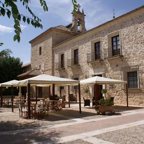 Edificio de piedra con terraza y mesas en un patio