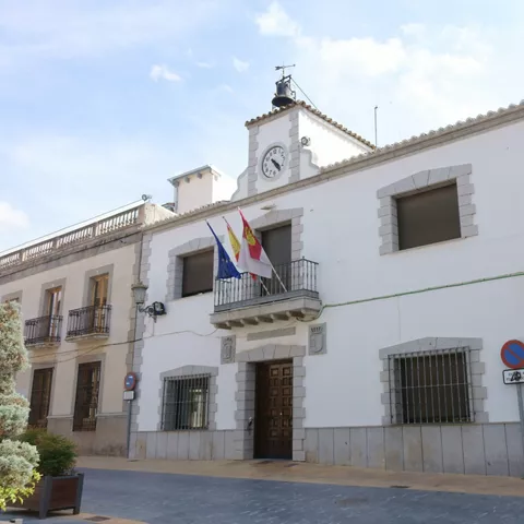 Fachada blanca del ayuntamiento con reloj y balcones