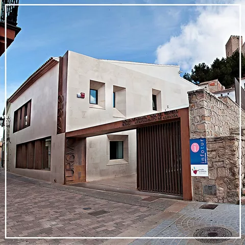 Edificio moderno de piedra clara con acceso cubierto y señalización turística.