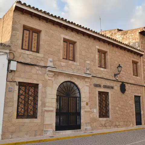 Fachada de edificio de piedra con ventanas simétricas y puerta en arco central.