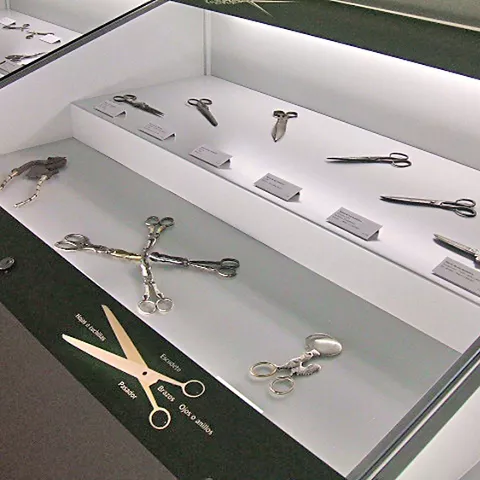 Vitrina con tijeras antiguas y utensilios metálicos expuestos en museo.