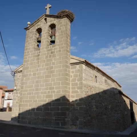 Iglesia de piedra con campanario, campanas y nido en la parte superior