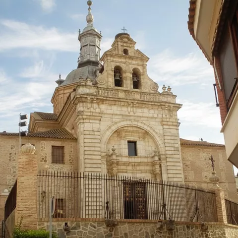 Fachada barroca de iglesia vista tras una verja