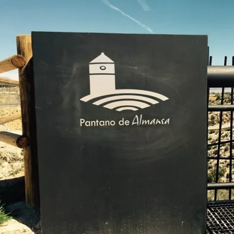 Panel informativo junto a una barandilla con vista al entorno natural.