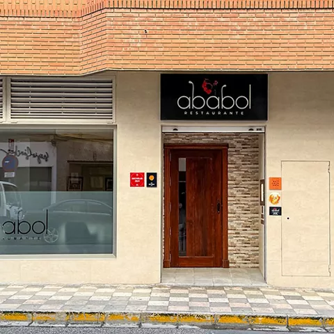 Fachada de restaurante con escaparate, puerta de madera y rótulo.