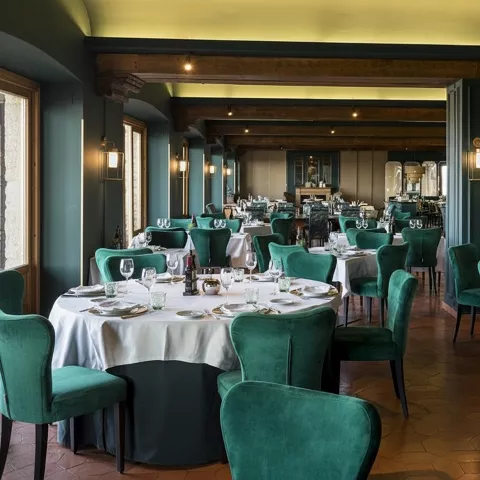 Comedor elegante con mesas redondas y sillas verdes