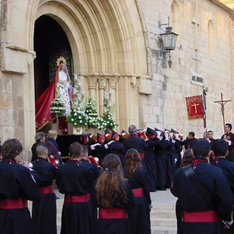 Imagen religiosa saliendo de un templo entre fieles y estandartes.