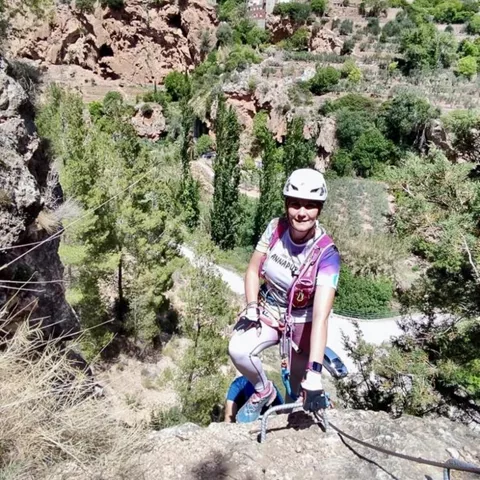 Persona equipada para vía ferrata en un tramo rocoso con valle al fondo