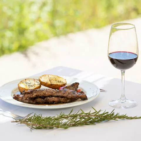 Carne a la parrilla con copa de vino tinto