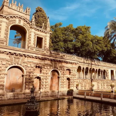 Fachada ornamentada con arquerías y estanque frontal.