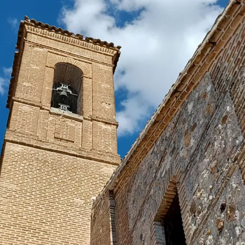 Detalle de torre de iglesia con campana y cielo azul