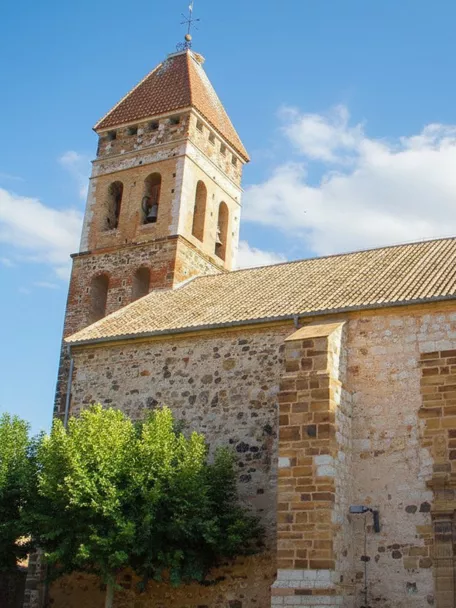 Iglesia parroquial de Argamasilla de Calatrava con torre campanario de ladrillo y portada de piedra.