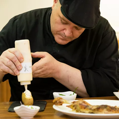 Cocinero decorando plato con salsa en cocina
