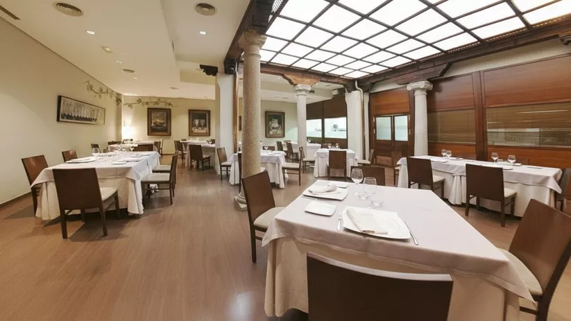 Comedor elegante con mesas vestidas y columnas de piedra