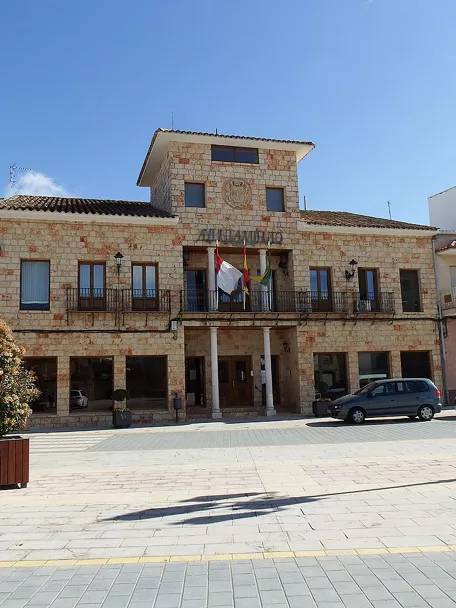 Edificio institucional de piedra en una plaza amplia.