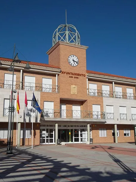Fachada de edificio institucional con reloj y plaza amplia al frente.
