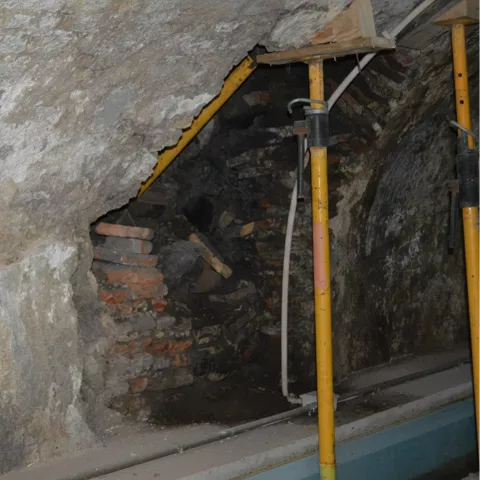 Espacio subterráneo con roca vista y puntales metálicos de refuerzo.