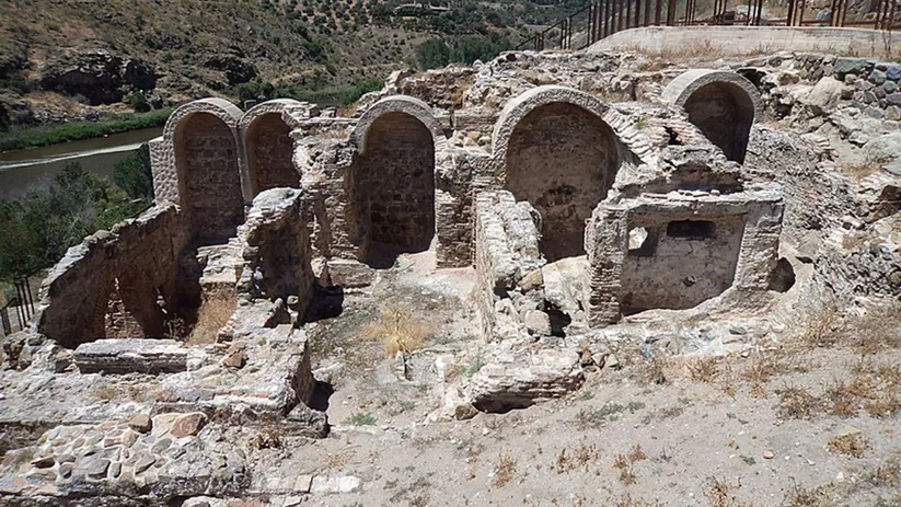 Restos de salas abovedadas de piedra en un entorno natural junto al río.