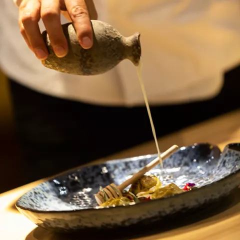 Vertido de salsa sobre plato de diseño artesanal