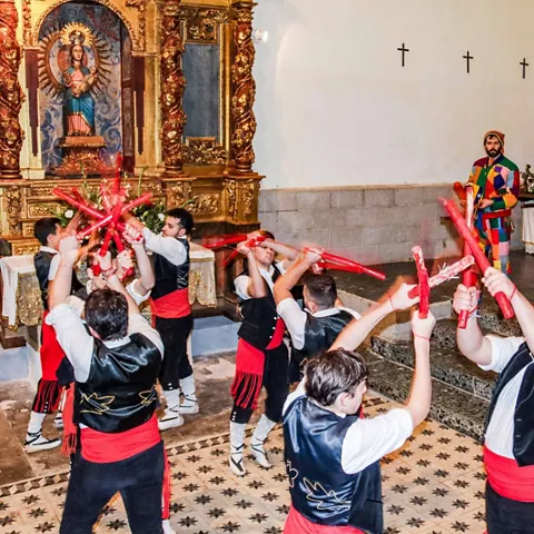 Danza con palos rojos dentro de una iglesia.